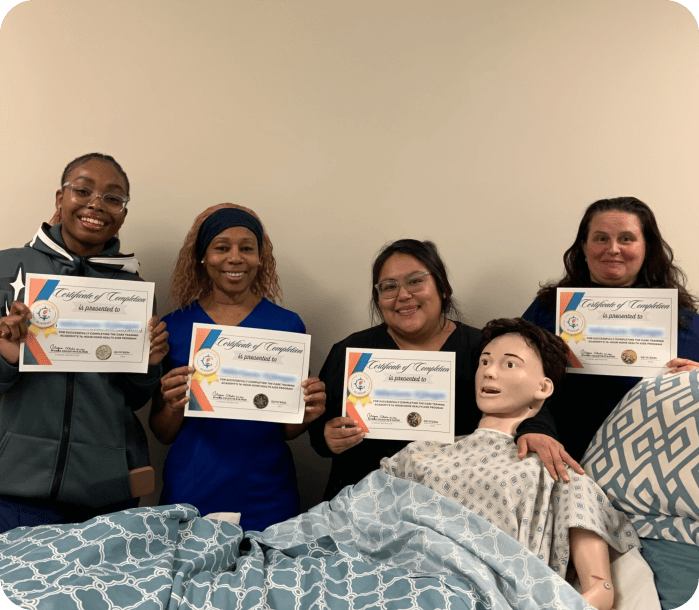 Four females holding certificates in front of a dummy person