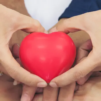 A group of hands holding a heart-shaped thing