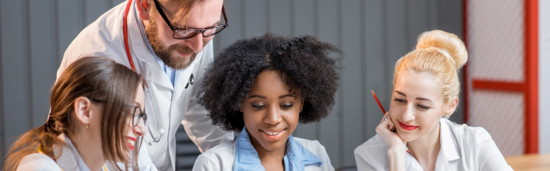 A doctor teaching three female medical staffs