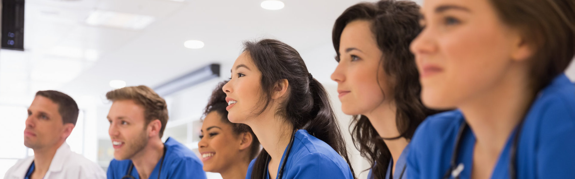 Six medical students smiling together while listening to a discussion