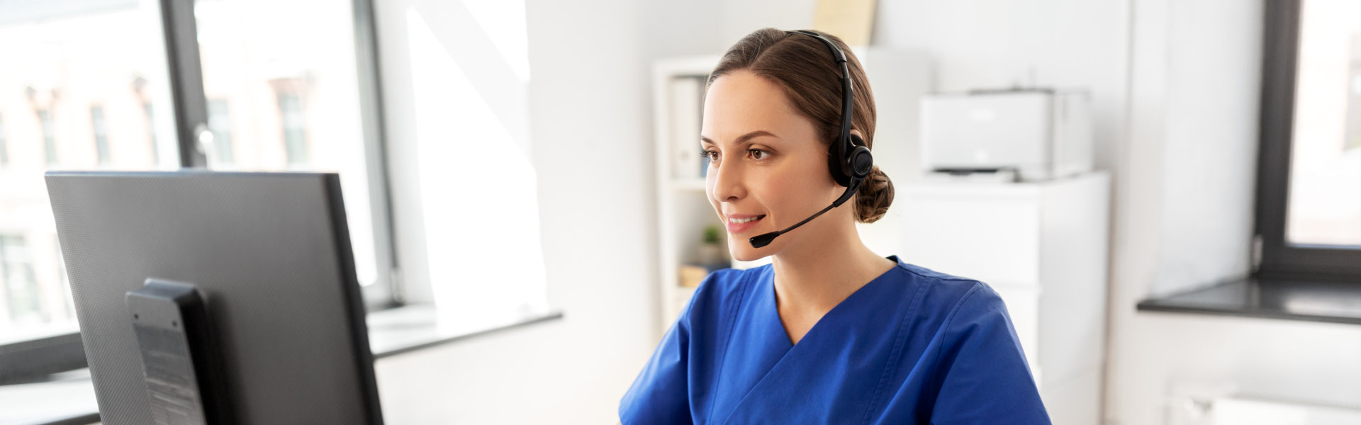 A female nurse wearing headphone and facing to a monitor