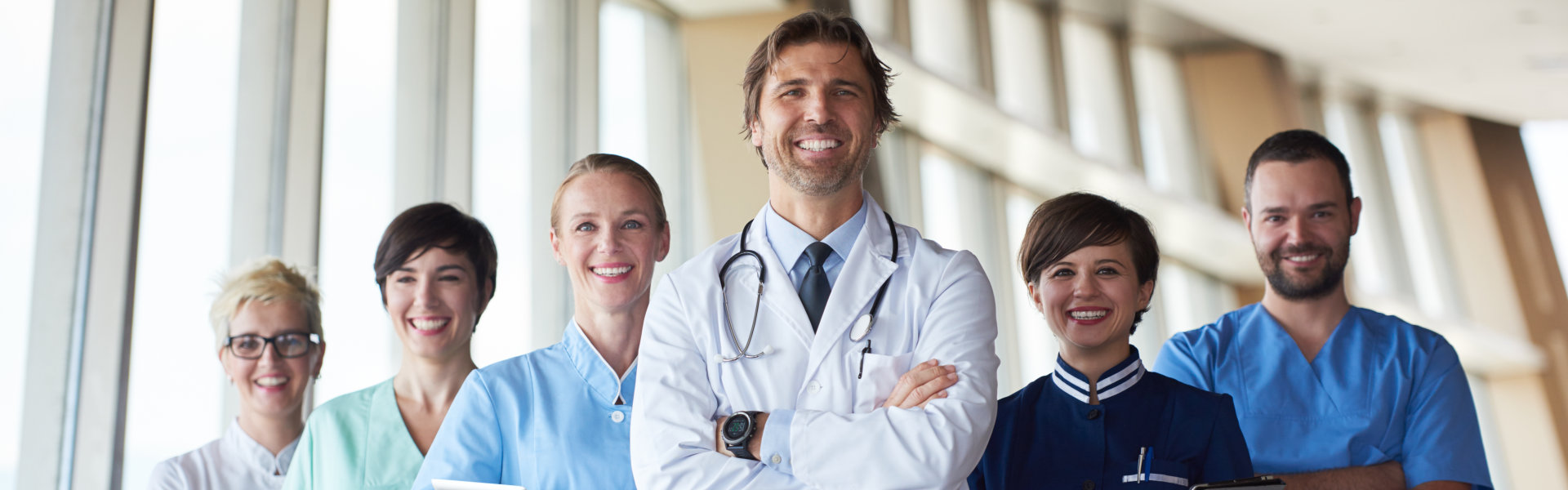 A doctor doing cross-arms pose together with five other medical staffs